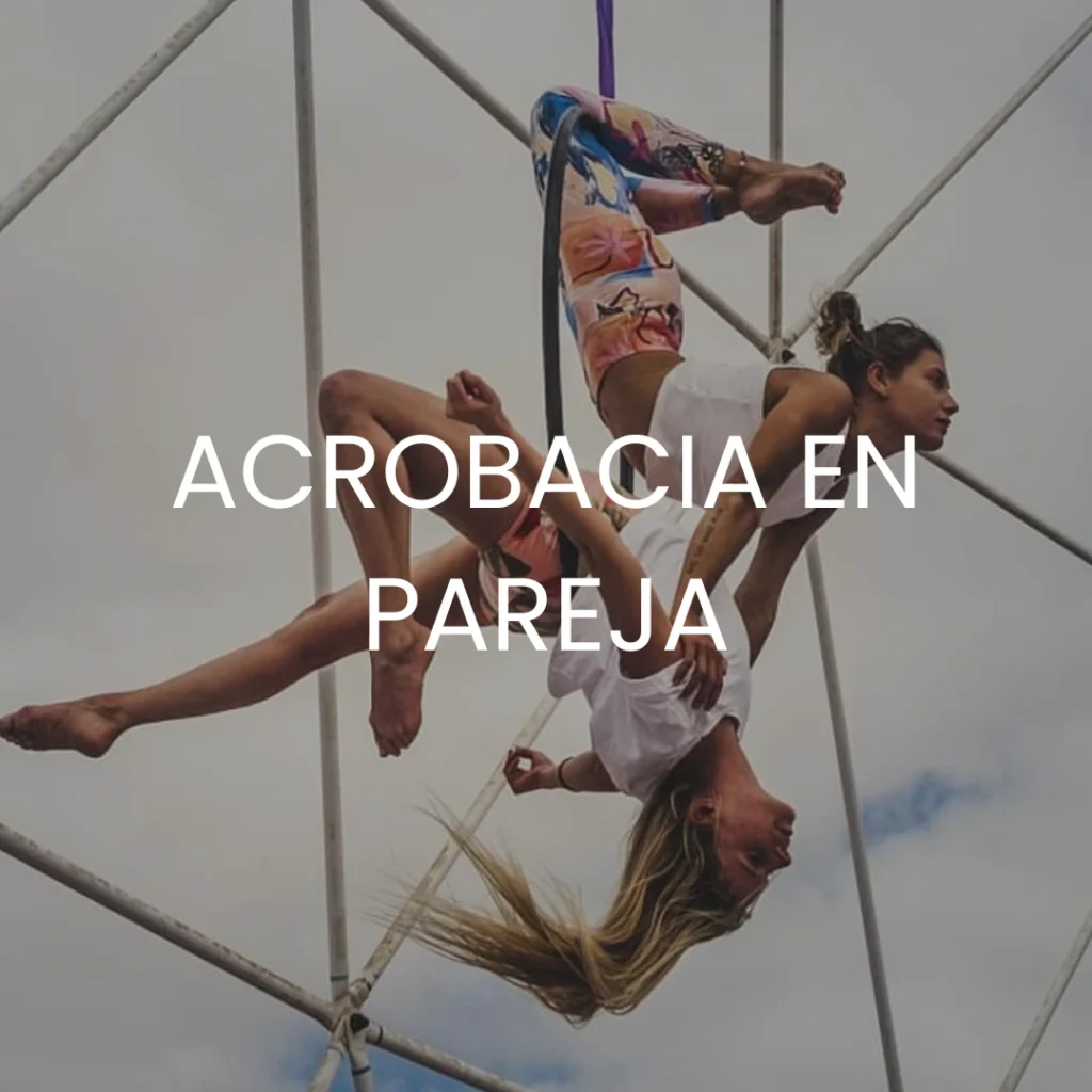 Dos mujeres haciendo un espectáculo de acrobacia aérea al aire libre con acrobacia en pareja escrito encima