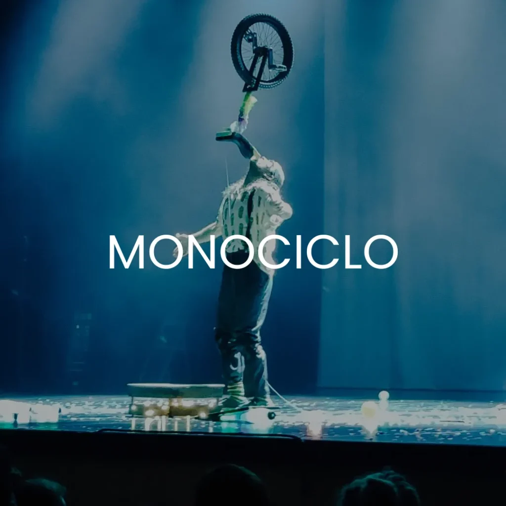 Un hombre haciendo un espectáculo con monociclo sobre un escenario con monociclo escrito encima