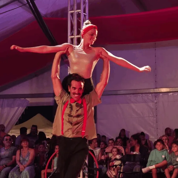 Johanna subida en Julián en una acrobacia en pareja con público de fondo